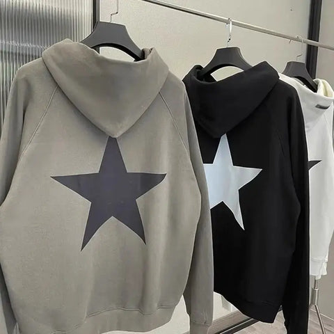 Men's star print long sleeve hoodies in gray, black, and white hanging on a rack.